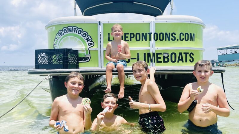 kids playing on crab island next to boat - lime pontoon rentals